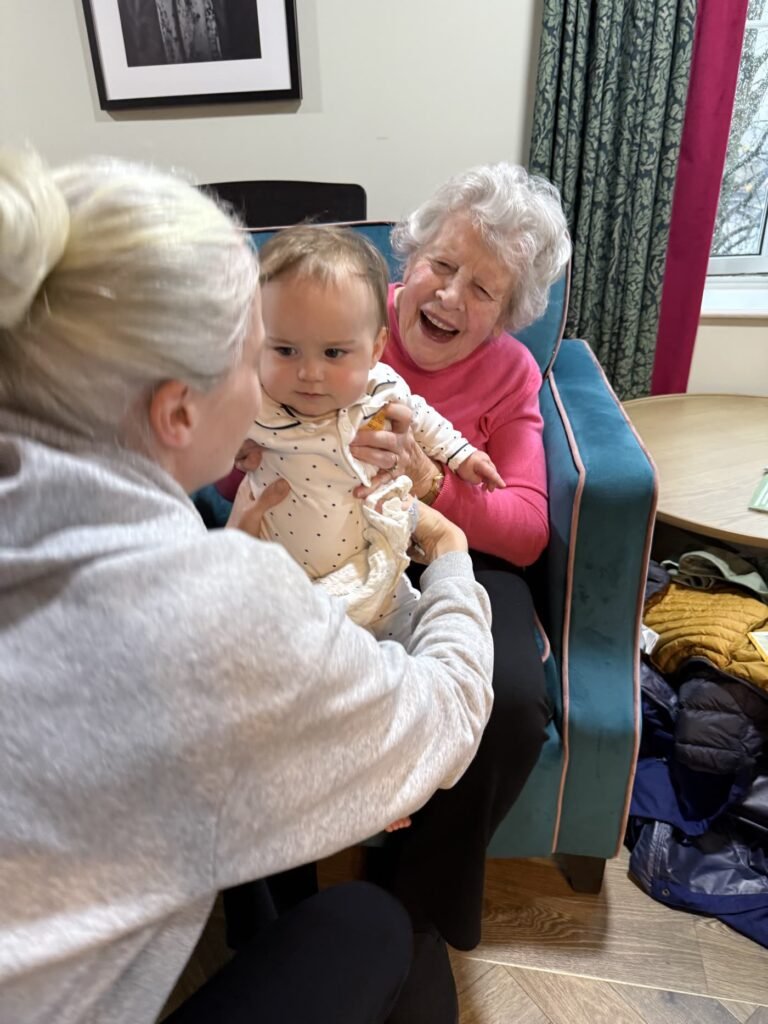 Care home resident laughing with a baby at a Rock Out Baby session